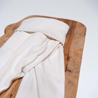 Nahaufnahme einer Abhaltehose. Detail zeigt den Schlitz und das Mitwachsbündchen am Bauch. Farbe der Hose ist natur, die Größe ist 56. Hose liegt auf Holz, das wiederum auf einem weißen Hintergrund.