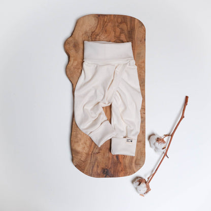 Eine Schlitzhose in natur auf Holz mit einem Baumwollzweig.