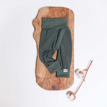 Eine Split-Pants in Natur, Größe 56 auf Holz mit einem Baumwollzweig.